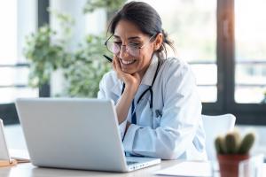 Smiling female doctor working with her laptop in the consultation.